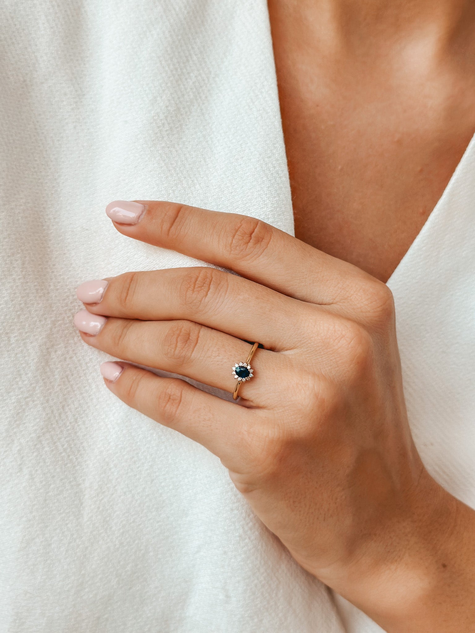 Zbliżenie dłoni z złotym pierścionkiem ozdobionym szafirem i diamentami