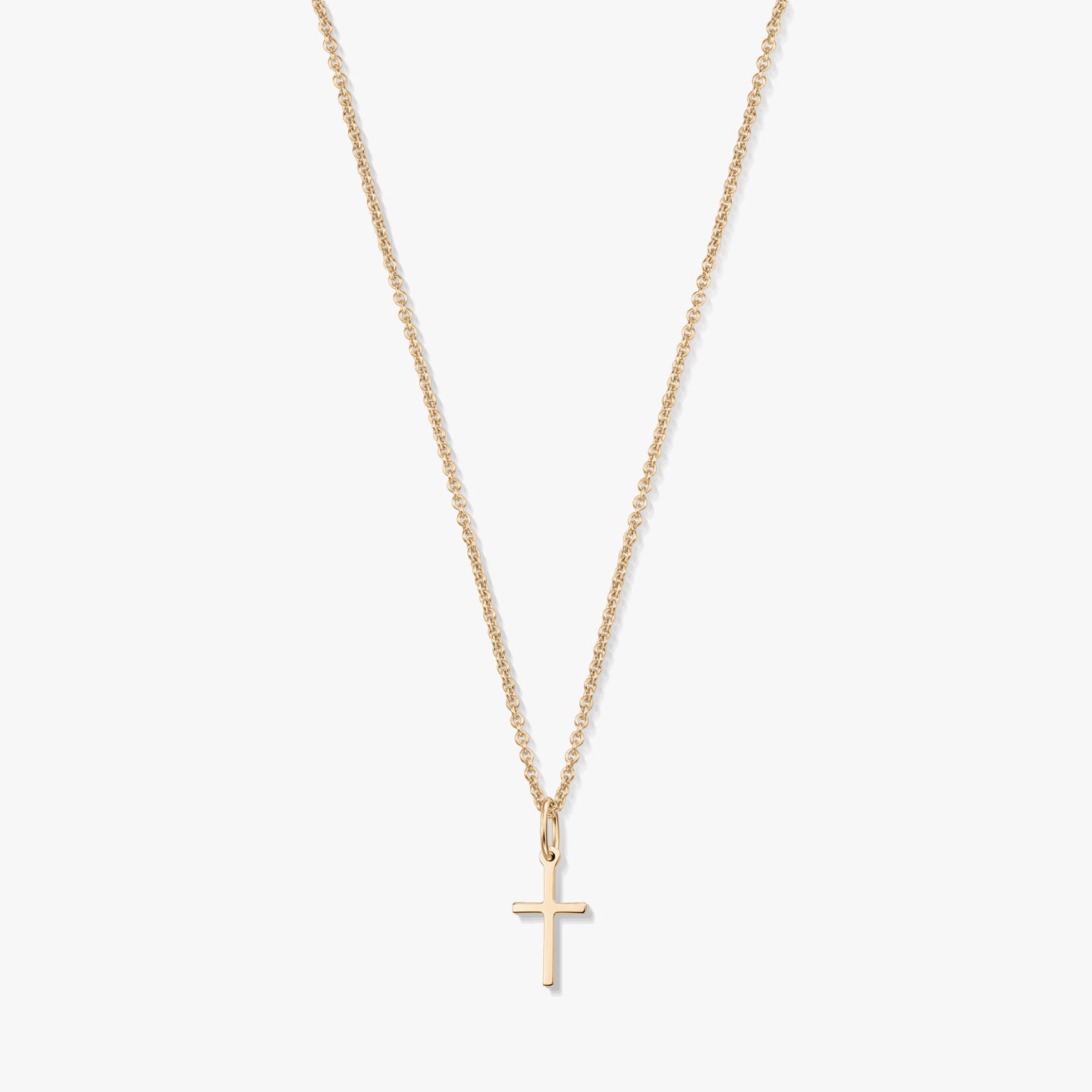 Minimalistyczny naszyjnik z żółtego złota 14K z małą zawieszką w kształcie krzyżyka na delikatnym łańcuszku, na białym tle.