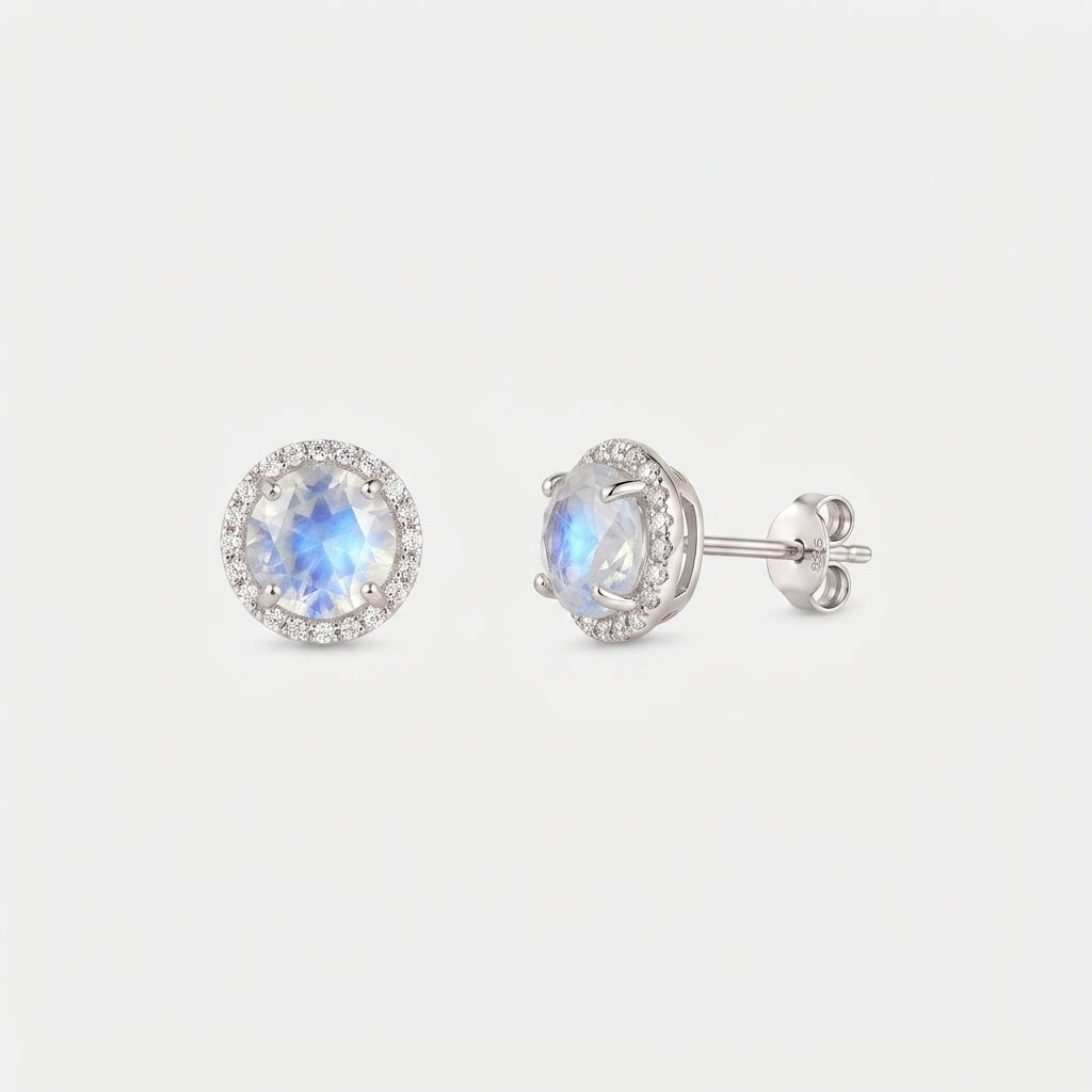 Para kolczyków sztyftów Keira ze srebra próby 925 z kamieniem księżycowym w oprawie typu halo; jedno ujęcie z przodu i drugie z boku z zapięciem typu motylek, na białym tle.