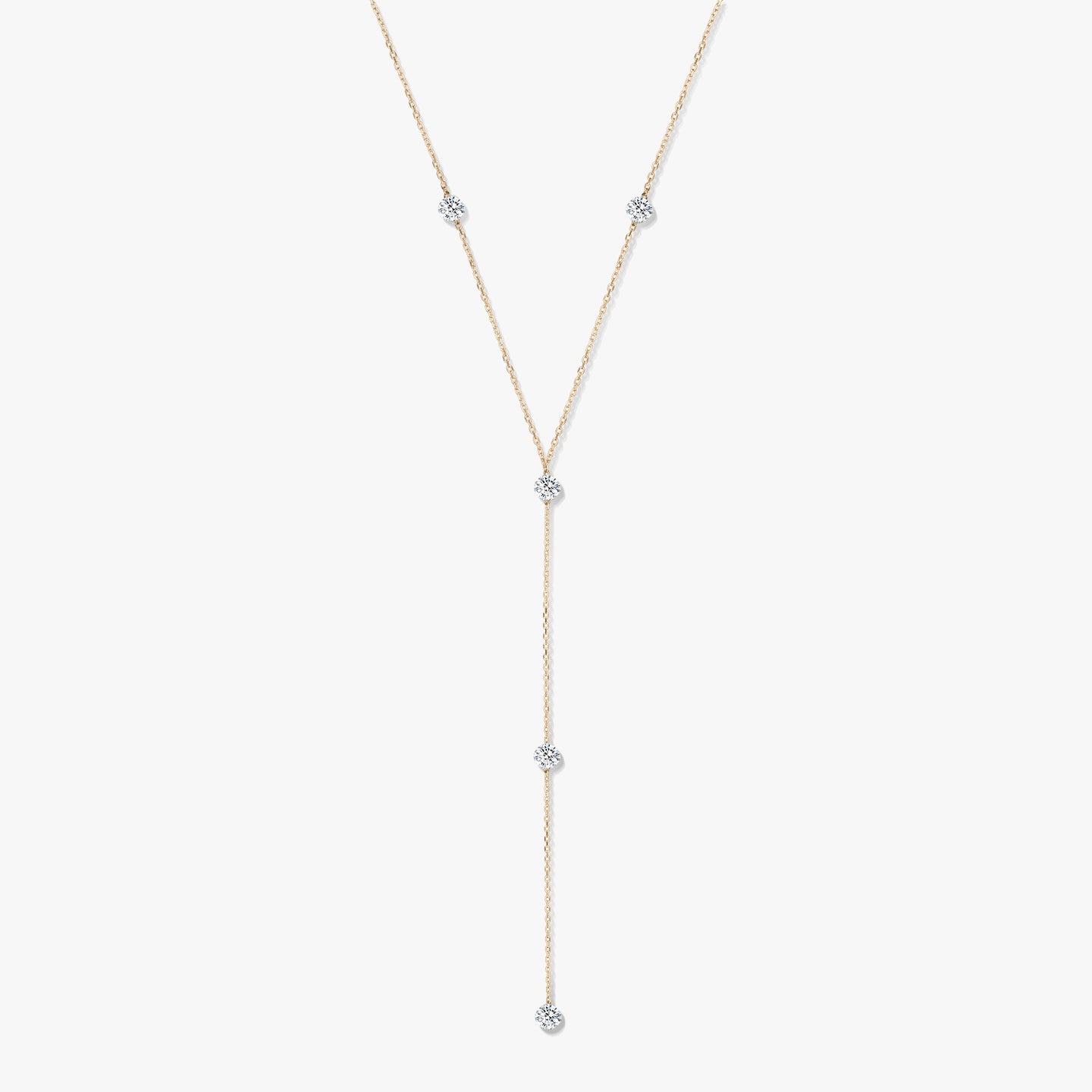 Naszyjnik typu lariat z żółtego złota 14K z pięcioma okrągłymi diamentami w oprawie typu bezel na białym tle.