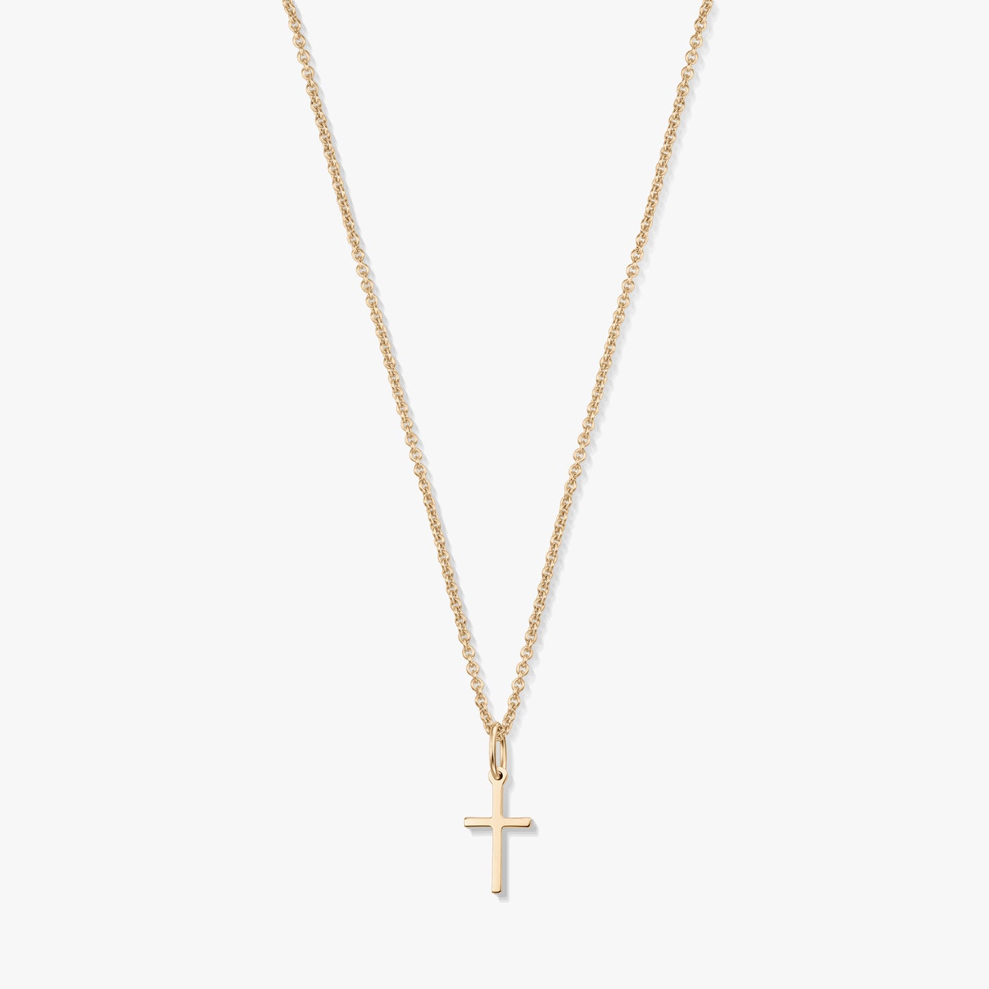 Minimalistyczny naszyjnik z żółtego złota 14K z małą zawieszką w kształcie krzyżyka na delikatnym łańcuszku, na białym tle.