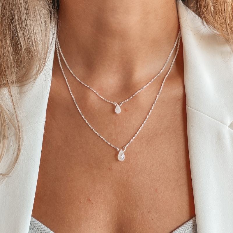 Zbliżenie osoby noszącej dwuwarstwowy naszyjnik srebrny z wisiorkami z kamieniem księżycowym.